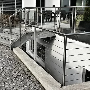 Treppenaufgang aus Stahl mit Geländer, das zu einem modernen Gebäude führt.