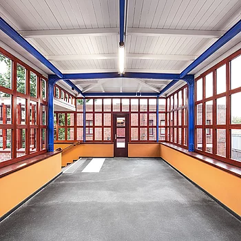 Innenansicht eines modernen Stahlbaugebäudes mit großen Fenstern in Rot und einer...