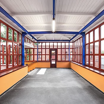 Innenansicht eines modernen Stahlbaugebäudes mit großen Fenstern in Rot und einer...