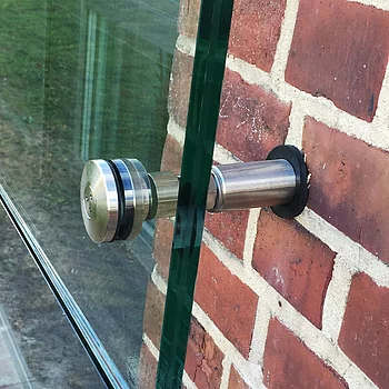 Detailaufnahme einer Schallschutzverglasung, die an einer roten Ziegelwand befestigt ist.