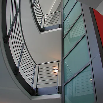 Blick auf eine geschwungene Treppe mit Metallgeländern und Glaswänden.