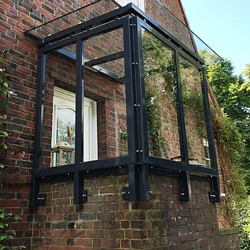 Vordachkonstruktion aus schwarzem Stahl und Glas, angebaut an einer Backsteinwand.