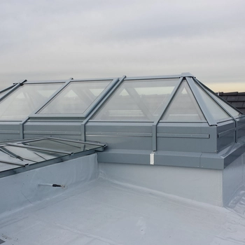 Dachansicht mit mehreren rechteckigen, transparenten Dachfenstern aus Glas, die auf einem...